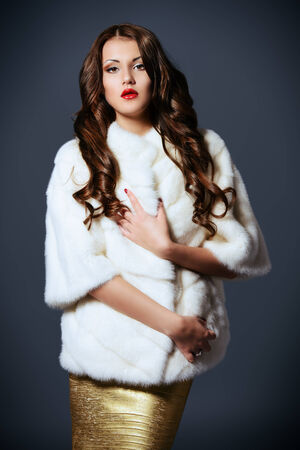 Fashion shot of a beautiful young woman in white fur coat.の写真素材