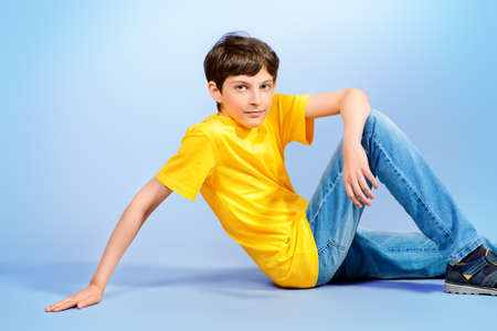 Smiling boy in casual clothes sitting on a floorの写真素材