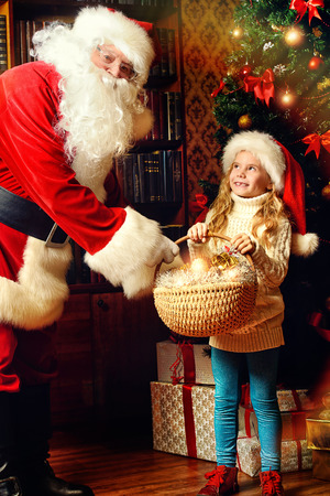 Happy little girl with Santa Claus and rejoice a giftの写真素材