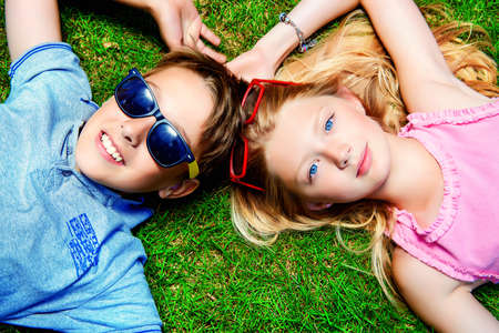 Two cheerful teenagers on the grass in the park. Summer. Friendship.の写真素材