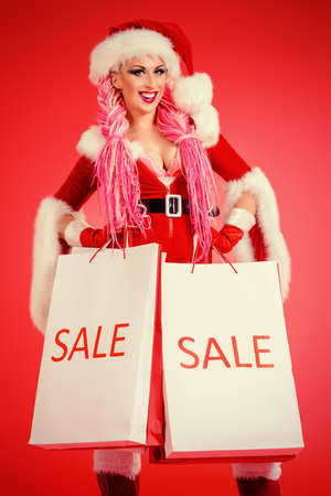 Portrait of a sexual babe dressed as Santa Claus holding shopping bags. Red background. Christmas.の写真素材