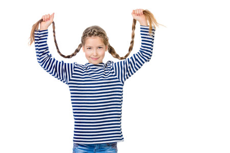 Cheerful teen girl in bright casual clothes holds her long braids. Hair, haircare. Studio shot....