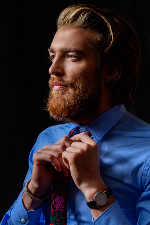 Close-up portrait of a respectable handsome man in a suit thoughtfully looking somewhere, dark background.の写真素材