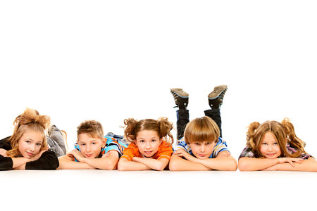 Happy children lying on a floor and smiling at camera. Isolated over white.の写真素材