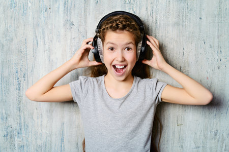 Cool teen girl enjoys the music in headphones. Studio shot.の写真素材