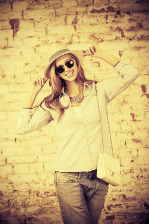 Beautiful young woman stands near the old brick wall in the city.の写真素材