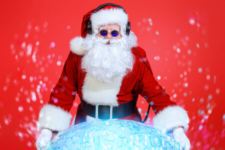 Santa Claus DJ near brilliant sparkling disco ball. Christmas celebration.の写真素材