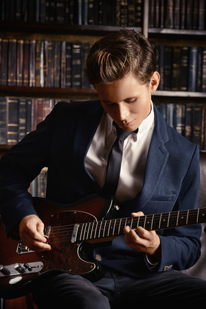 Handsome young man playing rock-n-roll music on his electric guitar. Retro, vintage style.の写真素材
