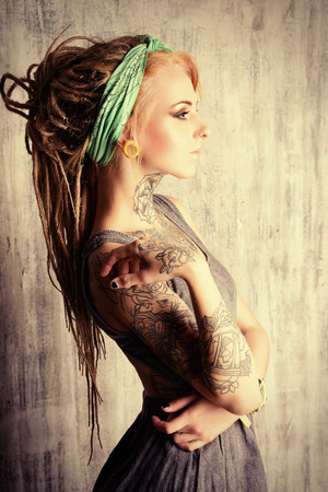 Sexual blonde girl with fascinating dreadlocks posing by the grunge wall. Pin-up style.の写真素材