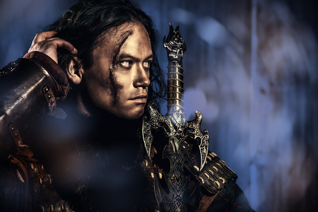 Close-up portrait of the ancient male warrior in armor holding sword. Historical character. Fantasy.の写真素材