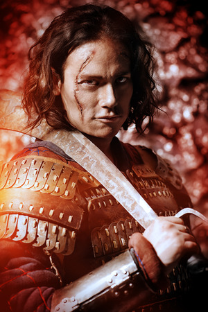 Close-up portrait of the ancient male warrior in armor holding sword. Historical character. Fantasy.の写真素材