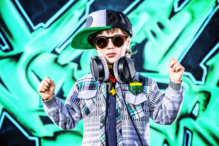 Trendy 7 year old boy on the street. Graffiti background. Modern generation.の写真素材