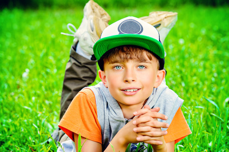 Smiling boy lying on a grass at a park. Summer day.の写真素材