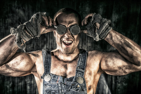 Portrait of a strong muscular man coal miner standing over dark grunge background. Mining industry. Art concept.の写真素材