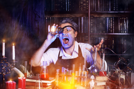 Portrait of a crazy medieval scientist working in his laboratory. Alchemist. Halloween.