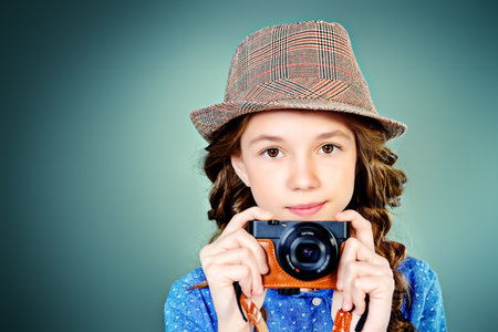 Cute smiling girl photographing on camera. Studio shot.の写真素材