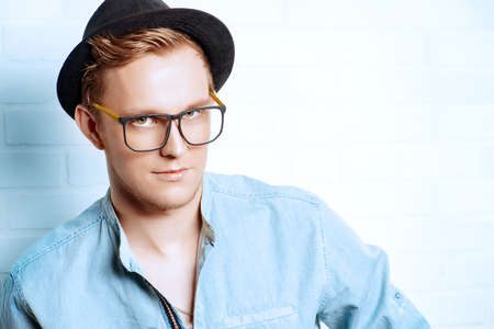Portrait of a modern young man standing by the brick wall. Beauty, fashion. Hipster style.の写真素材