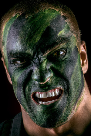 Close-up portrait of a furious soldier in war paint. Black background. Military, war. Special forces.の写真素材