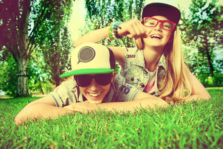 Two cheerful teenagers on the grass in the park. Summer. Friendship.の写真素材