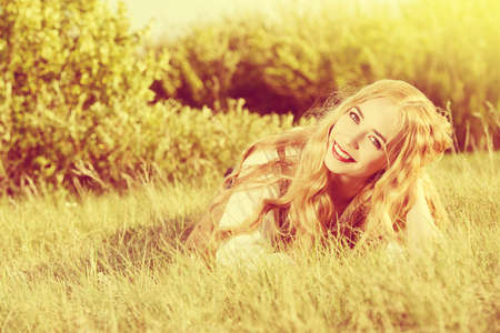Lovely smiling young woman with magnificent blonde hair in the meadow. Countryside. Summertime.の写真素材