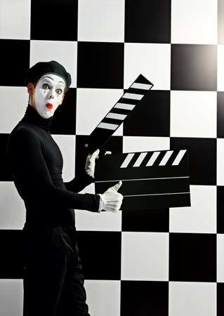 Movie actor and a mime posing with clapper board with different emotions. Chess board background. Cinema industry.の写真素材