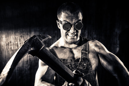 Muscular dirty coal miner with a pickaxe over dark grunge background. Mining industry. Art concept....