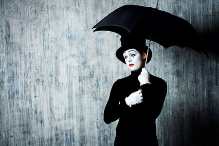 Portrait of a male mime artist standing under umbrella expressing sadness and loneliness. Grunge background.の写真素材