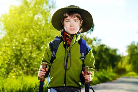 Portrait of a cute 7 years old boy in tourist clothes posing outdoor. Summer day.の写真素材