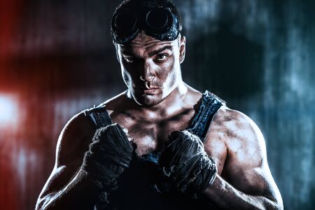 Brutal muscular dirty man expressing aggression over dark grunge background. Mining industry. World of the future, Apocalypse.の写真素材