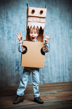Little dreamer boy playing with a cardboard dragon, dinosaur. Childhood. Fantasy, imagination.の写真素材