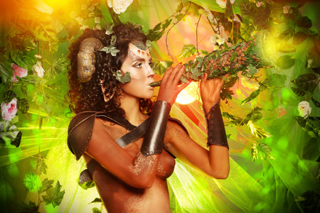 Fabulous Faun blowing the horn of plenty. Fantasy. Body painting.の写真素材