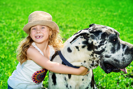 Happy little girl with her mastiff dog on a meadow in summer day.の写真素材