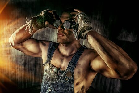 Portrait of a strong muscular man coal miner standing over dark grunge background. の写真素材