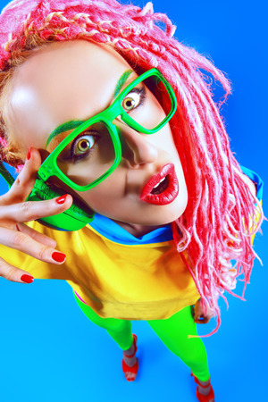 Ultra trendy DJ party girl in bright clothes, headphones and with bright dreadlocks. Disco, party. Show business. Bright fashion.の写真素材