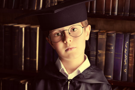 Smart boy stands in the library by the bookshelves with many old books. Educational concept. Science. Vintage style.の写真素材