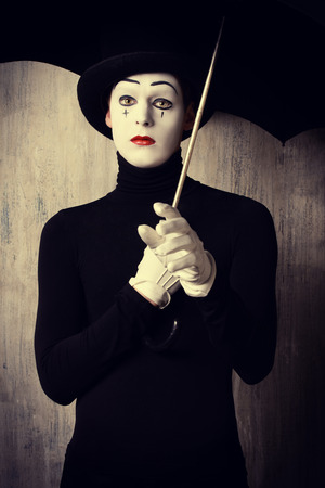 Portrait of a male mime artist standing under umbrella expressing sadness and lonelinessの写真素材
