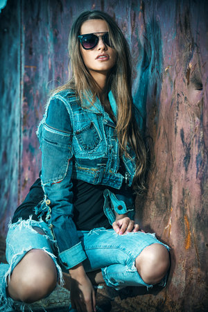 Stunning young woman in jeans clothes posing over urban background.の写真素材
