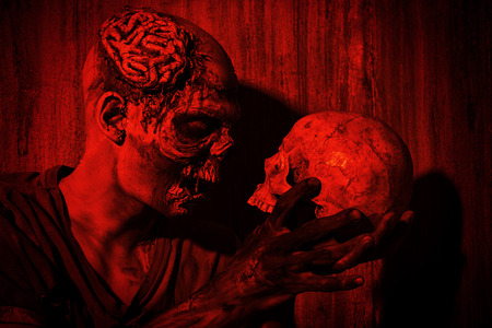 Frightening bloody zombie man with a skull in blood-red light. Halloween.の写真素材