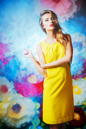 Fashion shot of a beautiful model posing on a background of bright large flowers. Beauty, fashion. Summer inspiration.の写真素材