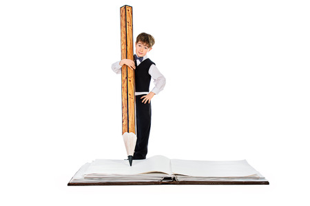 A boy writes with a big pencil in a big bookの写真素材