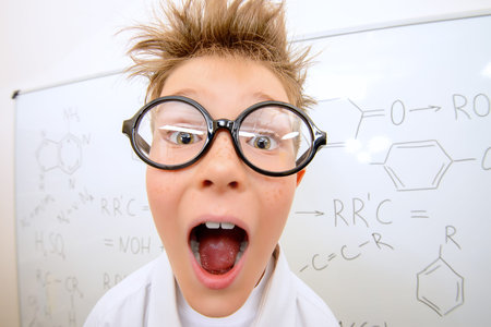 Funny schoolboy in big glasses standing by the school board and shouting. Chemistry. Science and...