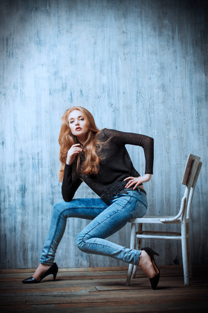 Beautiful blonde girl in jeans clothes posing by the grunge wall. Fashion.の写真素材