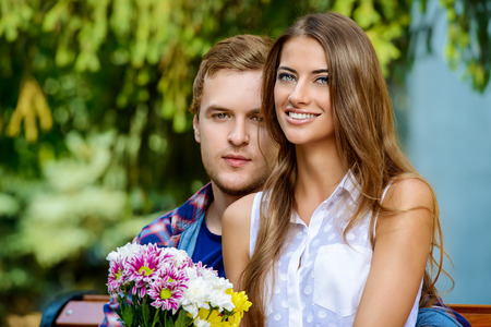 Young man giving flowers to his sweetheart girl. Sunny summer day.の写真素材