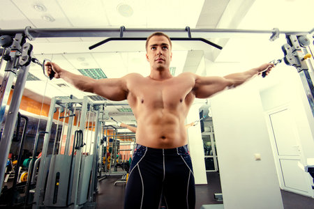 Athletic man working out with weight training equipment in a gym.  