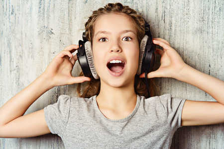 Cool teen girl enjoys the music in headphones. Studio shot.の写真素材