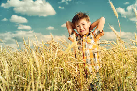 Cute smiling boy enjoyes summer day in the wheat field. Summer holidays.の写真素材