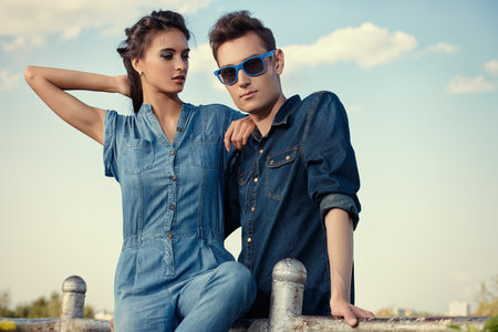 Portrait of a modern young people wearing jeans clothes over blue sky. Fashion shot.の写真素材