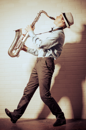 Young expressive musician playing the saxophone. Old style, retro.の写真素材