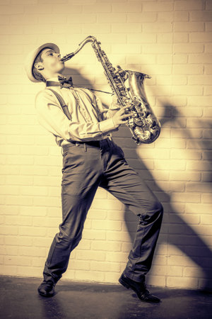 Young expressive musician playing the saxophone. Old style, retro.の写真素材