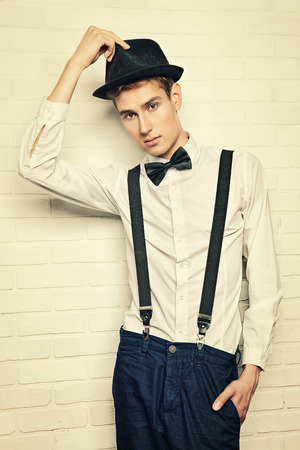 Portrait of a handsome young man in elegant suit posing by a white brick wall. Business.の写真素材